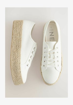 Sneakers din pânză albă pe o platformă, cu tălpi din fibră naturală împletesă și șireturi rotunde. Suprafață texturată cu gauri metalice argintii și detalii bej.