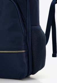 Tmavě modrý batoh vyrobený z odolného materiálu. Obsahuje zlatou kapsu se zipem a boční kapsu z prodyšné síťoviny. Hladký povrch, ergonomické popruhy.