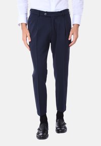 Pantaloni sartoriali blu navy con pieghe frontali, vestibilità slim, design a fronte piatto e texture liscia. Progettati con chiusura a bottone e passanti per cintura.
