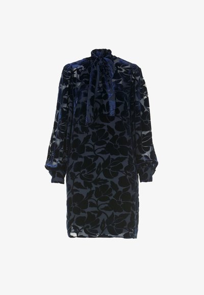 Tamno plava baršunasta haljina s cvjetnim uzorkom, visokim izrezom i detaljem u obliku mašne. Ima dugačke, nabiranim rukave i opušteni kroj.