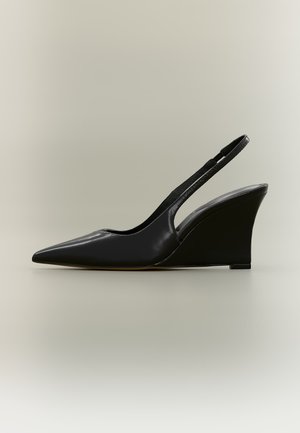 Czarny skórzany but typu slingback z ostrym noskiem i wysokim koturnem na neutralnym tle.