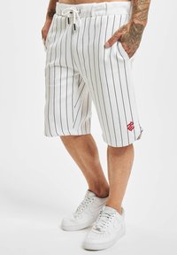 Shorts blancs à rayures, fabriqués en tissu léger, dotés d'une taille élastique avec cordon de serrage et de deux poches latérales. Accent logo rouge près de l'ourlet.