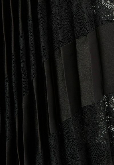 Robe noire avec des panneaux en dentelle et en satin, comprenant des sections plissées. La dentelle présente un motif floral, ajoutant texture et profondeur au design.