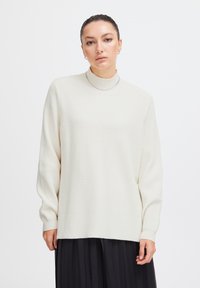 Pulover ribbed de culoare bej deschis, cu guler înalt și mâneci lungi, având o tivă dreaptă și un model texturat de tricot.
