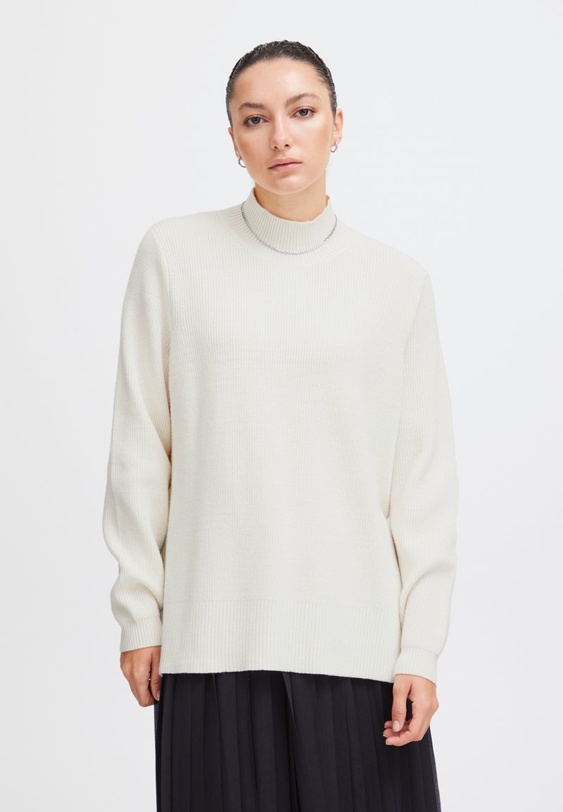 Maglione a coste di un beige chiaro con un alto collo e maniche lunghe, caratterizzato da un orlo dritto e un motivo a maglia testurizzato.