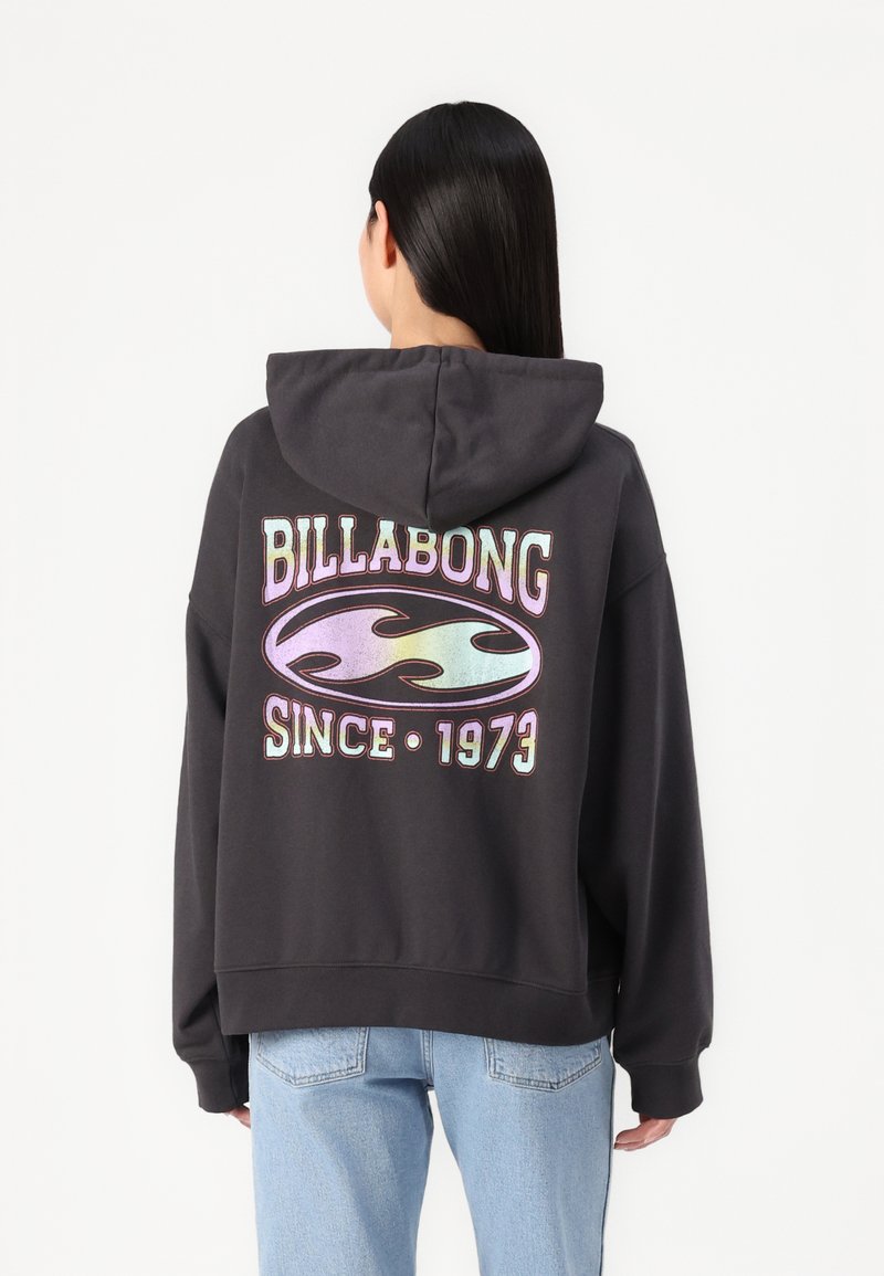 Felpa nera con cappuccio caratterizzata da una grande grafica iridescente con la scritta "BILLABONG" e "SINCE 1973" sul retro. Vestibilità ampia, con cappuccio regolabile.