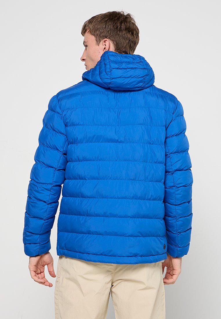 Giacca blu gonfiabile con motivo a cuciture orizzontali, cappuccio attaccato e texture liscia. Presenta polsini elastici e un leggero orlo.