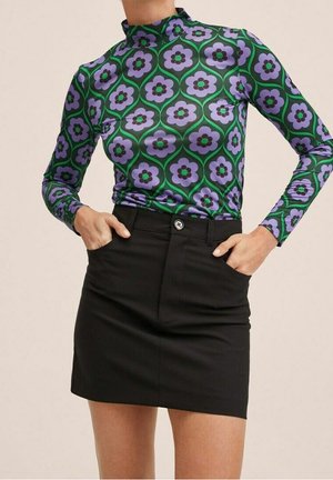 Pitkähihaisen topin kuosina violetteja ja vihreitä kukkia mustalla pohjalla, yhdistetty istuvaan mustaan minihameeseen, jossa on etupuolella nappisuljin.