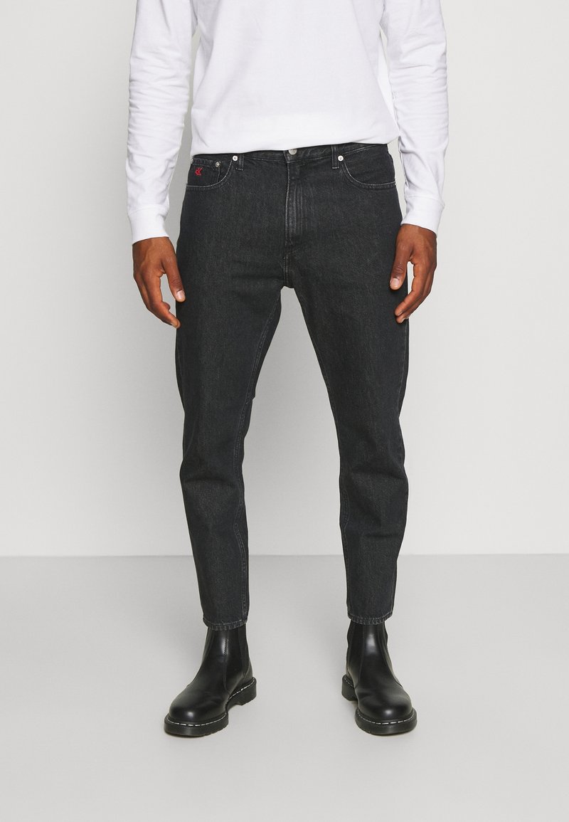 Svarta denimjeans med slim fit, med femficksdesign, metallknappstängning och subtil detalj i röd logotyp. Bärs med svarta ankelskålar.