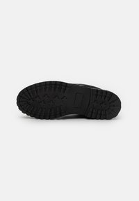 Black shoe sole featuring a deep tread pattern and rectangular area for branding. Durable rubber material with a textured finish.