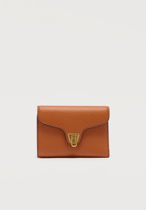 Kompakt brun læderpung med pebble-textur og lås i guldfarve, fotograferet mod en simpel lys baggrund.