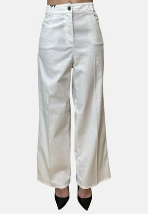 Pantaloni bianchi a vita alta e gamba larga con chiusura frontale con bottone e zip, indossati con tacchi neri a punta, mostrati dalla vita fino ai piedi.