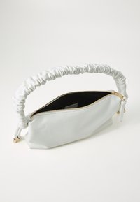 Sac à main en cuir blanc avec poignée froncée et fermeture éclair dorée partiellement ouverte, montrant un intérieur noir sur un fond blanc uni.