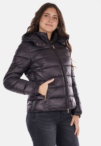 Giacca a vento in un viola scuro con finitura lucida, dotata di cappuccio, chiusura lampo frontale e tasche, polsini a coste e cuciture orizzontali.