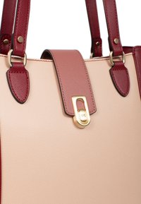 Borsa beige in materiale testurizzato, con manici bordeaux e una chiusura dorata. Presenta una cucitura decorativa e dettagli sui manici e sulla chiusura.