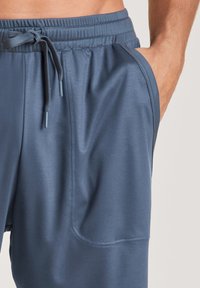 Dark blue athletic shorts made of lightweight, smooth fabric. Features an elastic waistband with drawstring and side pockets.