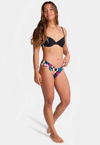 Black bikini top with molded cups, paired with multicolored floral print hipster bottoms. Smooth fabric, minimal coverage design.
