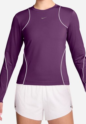 Lila långärmad träningströja med grå detaljer och en åtsittande design, tillverkad av fukttransporterande tyg, kombinerad med vita shorts.