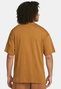 Överdimensionerad t-shirt med korta ärmar i senapsgul färg, tillverkad av mjukt material, med en enfärgad baksida utan synliga logotyper eller mönster.