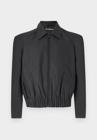 Schwarze, cropped Jacke aus glattem Stoff mit Reißverschluss vorne, spitzem Kragen und elastischem Bund, seitlichen Taschen und langen Ärmeln.