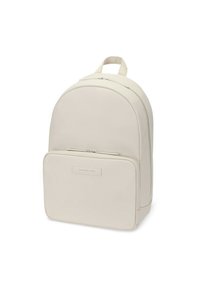 Beżowy plecak o gładkiej fakturze, zaokrąglonym kształcie, z podwójnymi zamkami błyskawicznymi i przednią kieszenią z prostokątną łatką z logo.