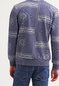 Felpa blu navy con motivi geometrici in grigio, dotata di collo a giro e polsini e orlo a coste. Vestibilità casual.
