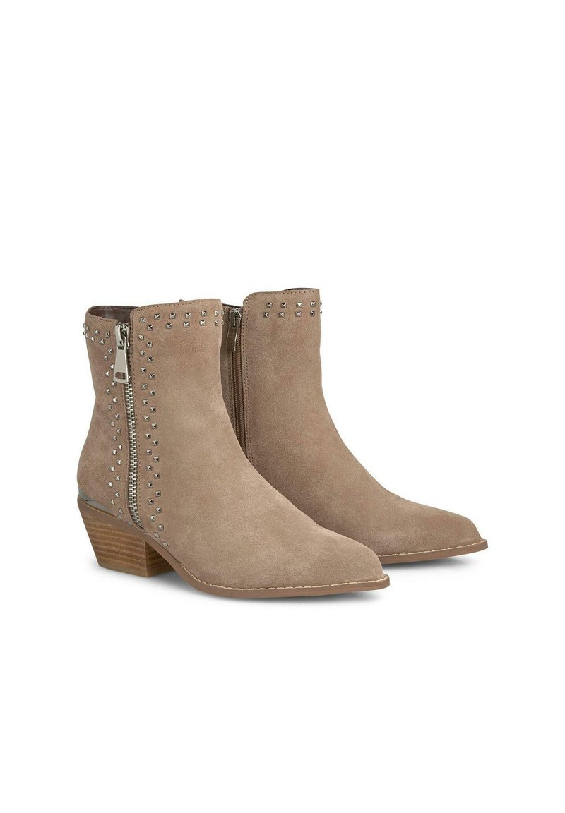 Botas de ante hasta el tobillo en un color beige claro con punteras afiladas, cremalleras laterales y detalles de tachuelas plateadas a lo largo del eje. Tacones de bloque con textura de madera.