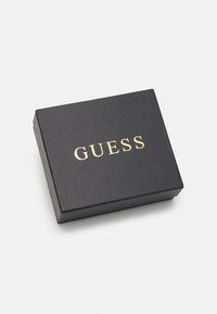 Black cardboard box with a rectangular shape, featuring a gold "GUESS" logo on the top, smooth texture, and a matte finish.
