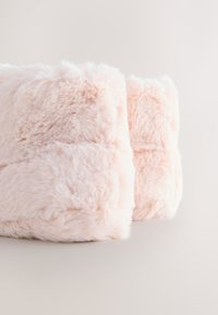 Růžové polštáře z umělé kožešiny s hebkou texturou, obdélníkového tvaru a s prošitými detaily. Měkký povrch s mírným leskem, vhodné pro dekoraci.