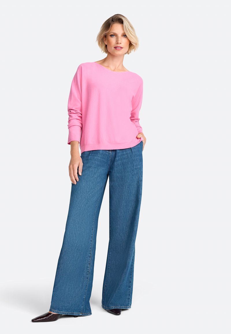Pink long-sleeve shirt paired with loose blue denim jeans. The jeans feature a straight cut and frayed hem, completing a relaxed look.