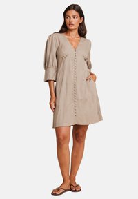 Beige lin kjole med V-hals, puffede ærmer og knapdetaljer ned langs fronten. Har en afslappet pasform og sidelommer.