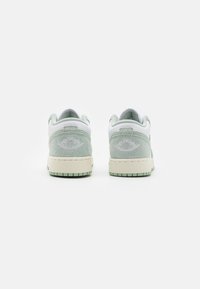 Sneaker in suede e pelle verde chiaro con una finitura texturizzata, dotate di una suola in gomma chiara e dettagli del logo in rilievo sul tallone.