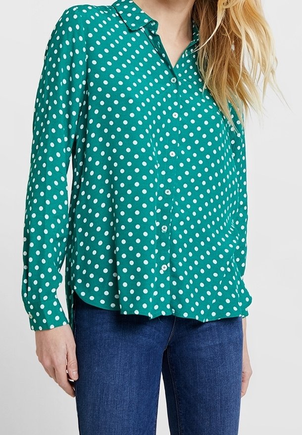 Chemise verte à manches longues avec pois blancs, col, fermeture boutonnée sur le devant, ourlet arrondi, en tissu léger et lisse.