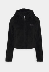 Svart, kort zip-up hoodie gjord av mjukt, fluffigt tyg. Har en huva, framzipper och en diskret logopatch på bröstet.