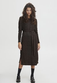 Abito lungo lavorato a maglia con righe verticali, tonalità di nero e oro, vita con cintura, maniche lunghe, spacchi laterali e lunghezza a metà polpaccio.