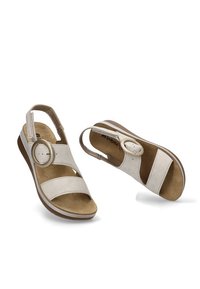 Sandalias slingback de color beige claro con dos tiras anchas, un acento de hebilla circular y una plantilla acolchada con una suela de cuña baja.