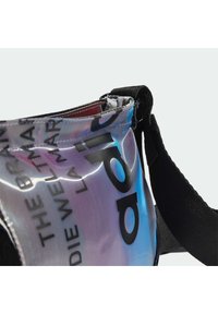 Przezroczysta torebka na ramię o iryzującym wykończeniu, z wyraźnym czarnym napisem i regulowanym czarnym paskiem do noszenia.