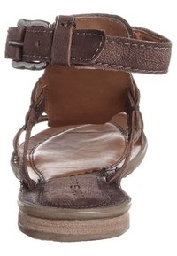 Brun lädersandal med justerbart ankelsnöre, öppen tådesign, slät yttersula och texturerad innersula. Har sömnadsdetaljer.