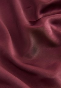 Bordeaux satin stof med en glat, skinnende tekstur og subtile draperinger og flydende folder, der reflekterer lyset graciøst.