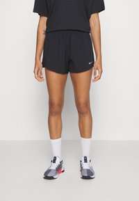 Svarta sportshorts med elastiskt midjeband, tillsammans med vita ankle-sockar och flerfärgade Nike löparskor. Enkelt, funktionellt design.