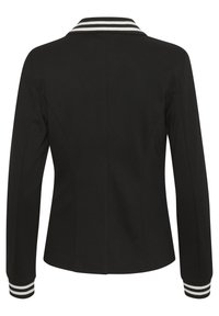 Musta räätälöity takki, jossa raidallinen valkoinen kaulus ja kalvosimet. Sileä pinta, pitkät hihat ja vartalonmyötäinen leikkaus. Siisti selkädesign.