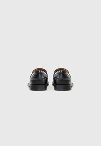 Black leather shoes with a smooth texture, low heel, and contrasting white stitching along the back and sides.