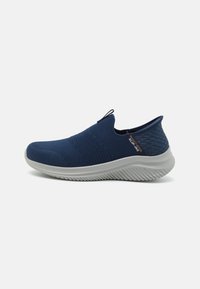 Marineblå slip-on sko med teksturert strikket overdel og polstret grå såle, med et løftestropp på hælen for enkel påføring.