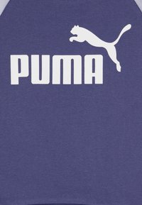 Violeta sporta krekls ar izteiksmīgu baltu "PUMA" logo un lecoša puma grafiku. Izgatavots no mīkstas, tekstūras auduma ar apaļu kakla izgriezumu.