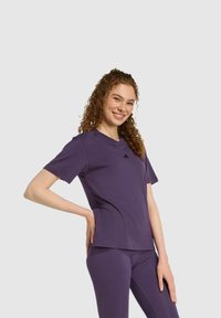 Lila Sport-T-Shirt aus weichem Stoff mit kurzen Ärmeln und Rundhalsausschnitt, mit einem dezenten Logo-Detail auf der Brust.