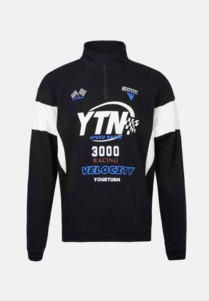 Pullover bianco e nero con design a mezza zip, caratterizzato da stampe grafiche e dettagli a scacchi. Realizzato in un morbido tessuto testurizzato.