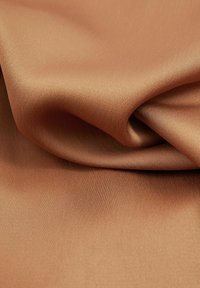 Copper-colored satin fabric with a smooth, glossy texture, draped and folded to show its soft sheen and flowing design.