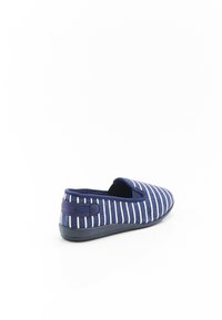 Scarpa slip-on navy con strisce verticali bianche, parte superiore in tessuto, pannelli laterali elastici e suola in gomma testurizzata. Sul retro è presente un piccolo anello in tessuto.