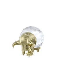 Guldfärgad djurfigur med böjda horn, som håller en blomma, placerad under en klar, fasetterad kristallkula. Slät textur, dekorativ detalj.