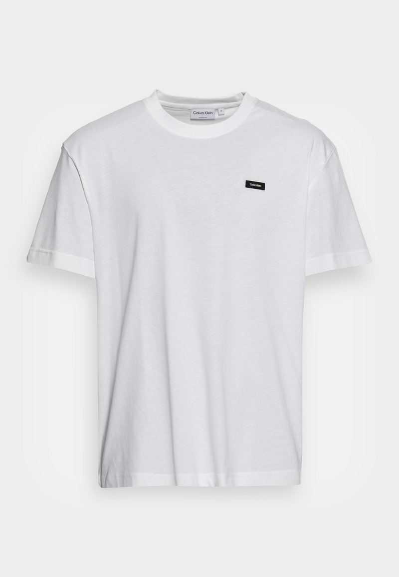 T-shirt blanc à manches courtes et col rond avec un petit patch noir du logo Calvin Klein sur la poitrine gauche.